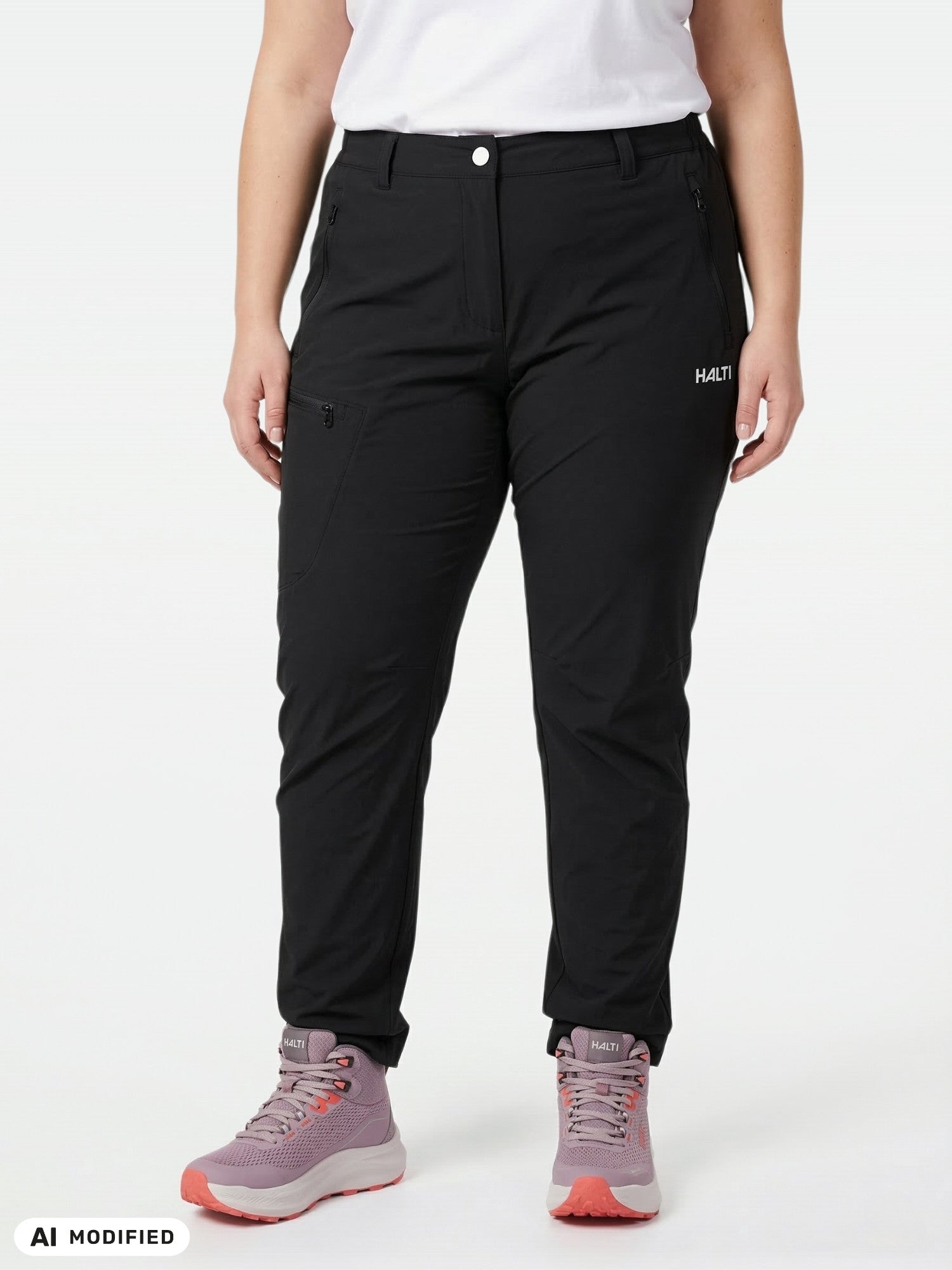 Modellen bär Halti Pallas X-stretch Outdoor Byxor Dam Plus, en vit skjorta och rosa vandringskängor framför en vit bakgrund.