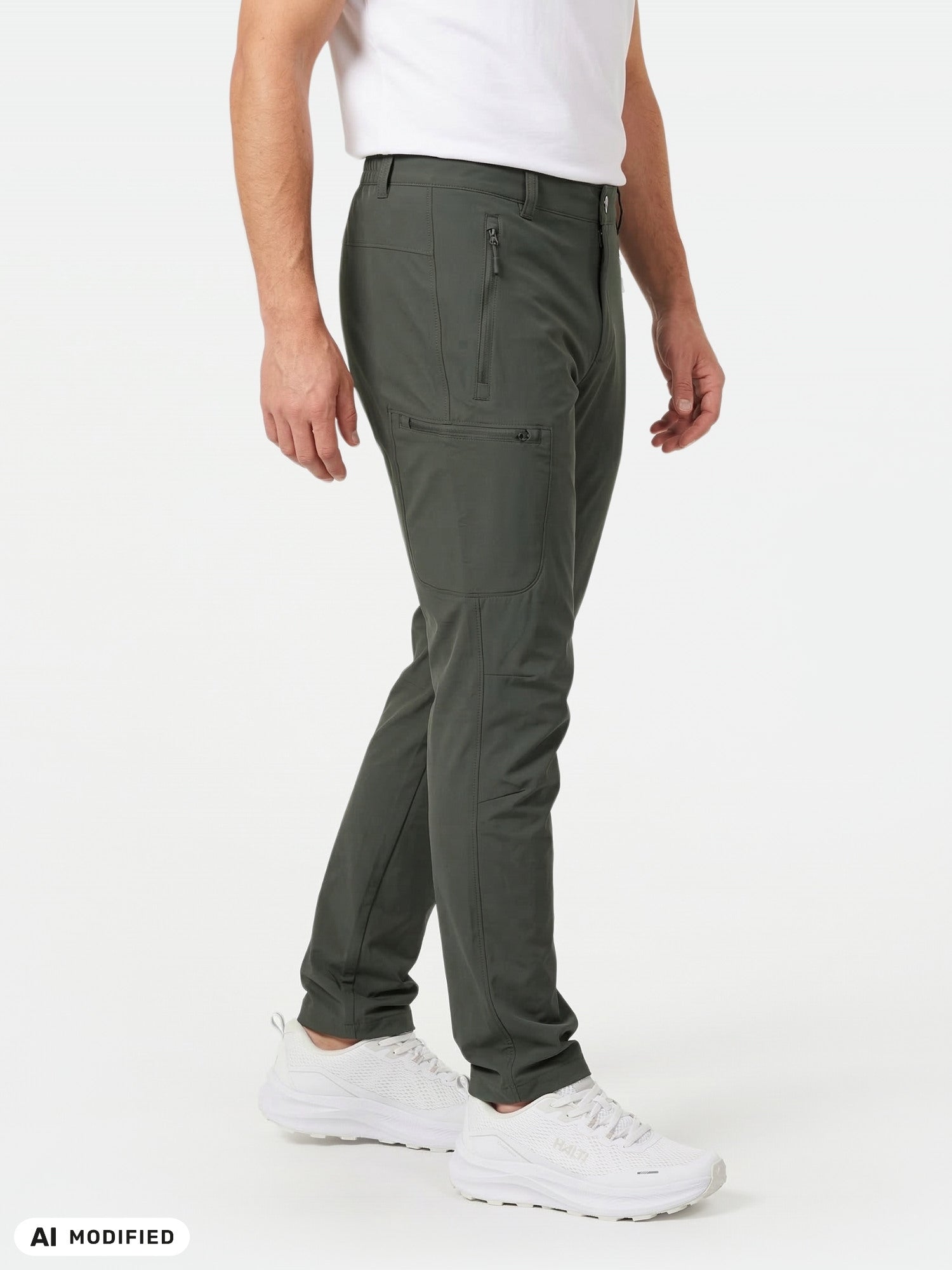 En person klädd i Halti Pallas X-stretch Outdoor Byxor Herr, vita sneakers och en t-shirt står framför en enfärgad bakgrund.