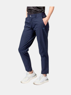 Personen bär Halti Drive X-stretch Chinos Dam i marinblå färg, en svart skjorta och vita sneakers med händerna i fickorna.