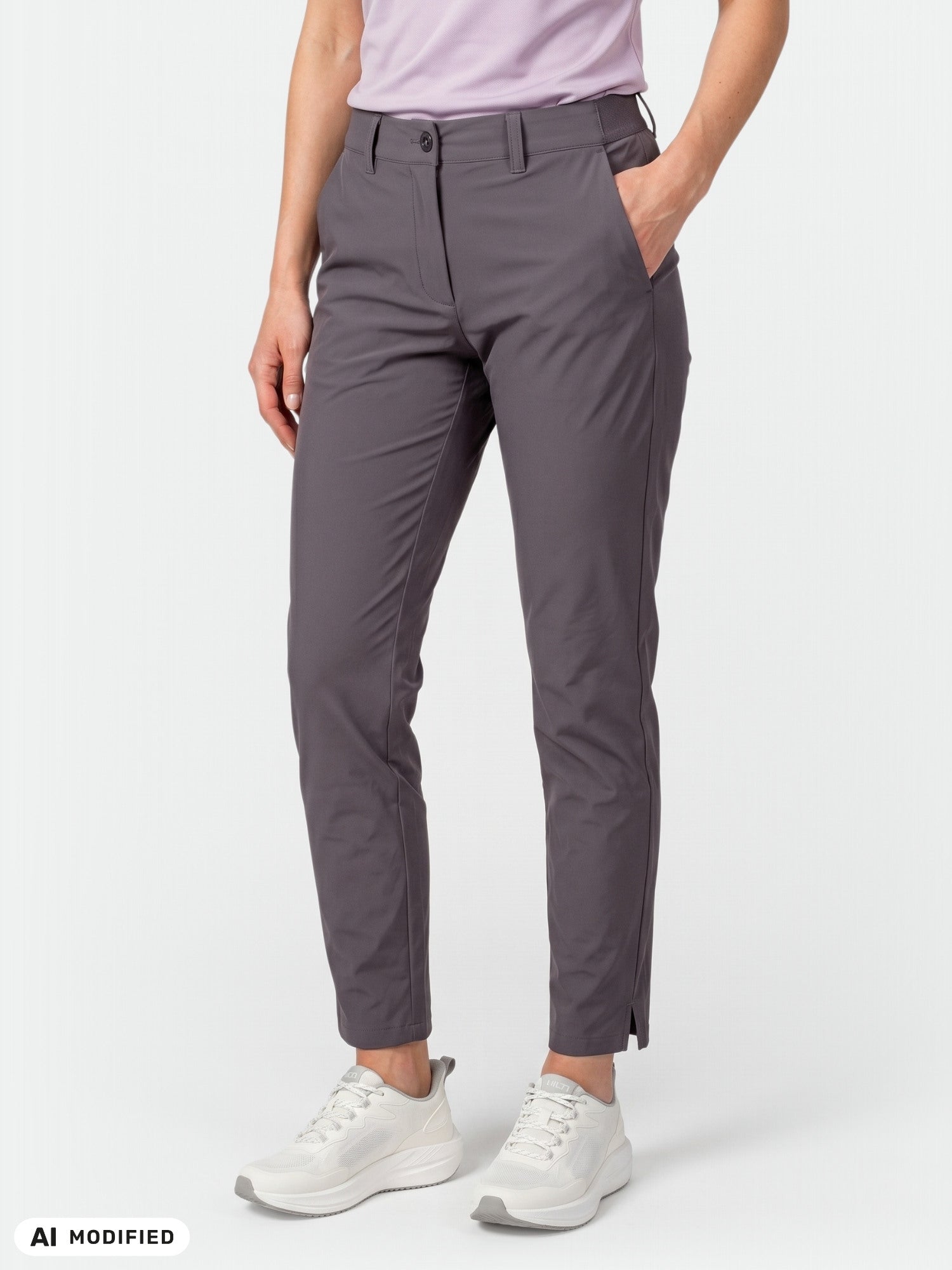 Personen bär ett par grå Halti Drive X-stretch Chinos Dam, en ljuslila skjorta och vita sneakers; händerna i fickorna.
