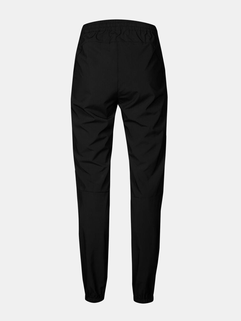 Bakifrån på Halti Grets Joggers Dam med elastisk linning och muddar, mot en enfärgad ljus bakgrund.