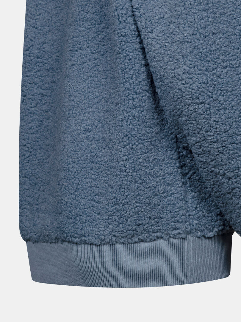 Närbild på Halti Lykky Fleece Jacka Dam i blått, med ribbad nederkant och mjukt, strukturerat sherpa-fleece-tyg.