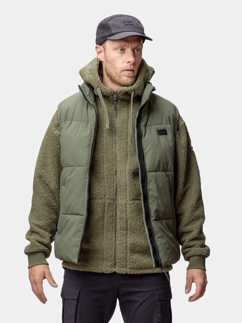 En man i Halti Penger Classic Puffer Väst Herr tittar framåt mot en enfärgad bakgrund.