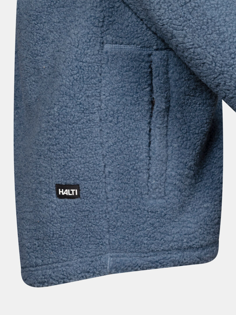 Närbild på en blå Lykky Fleece Jacka Herr-ficka med Halti-etiketten sydd nära nederkanten.