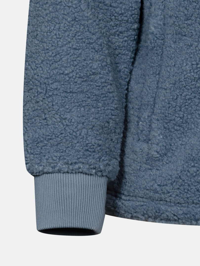 Närbild på ärmen på Halti Lykky Fleece Jacka Herr med ribbade manschetter, där den mysiga teddy-strukturen framhävs mot en enfärgad bakgrund.