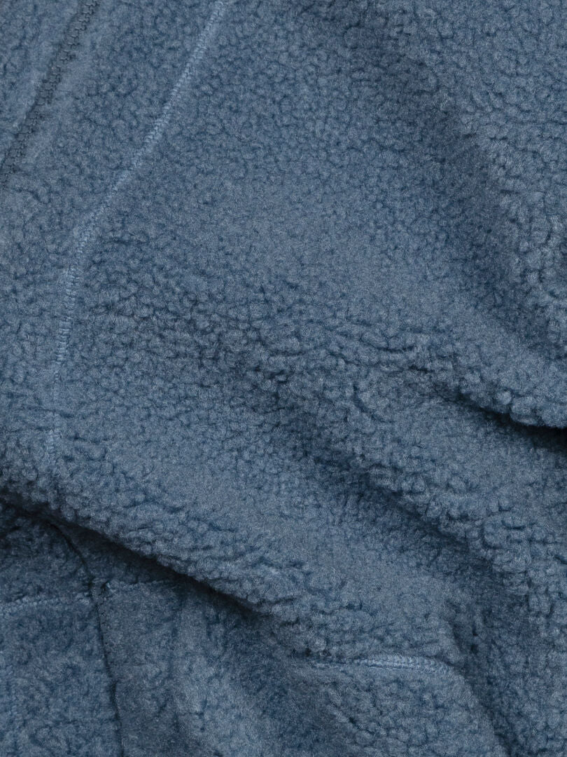 Närbild på tyget till Halti Lykky Fleece Jacka Herr, som visar dess mjuka teddy-struktur och lätt skrynkliga utseende.