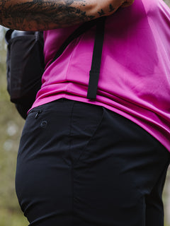 En person i en rosa skjorta och Halti Drive X-stretch Capribyxor Dam Plus, tatueringar synliga, utomhus, suddig bakgrund.