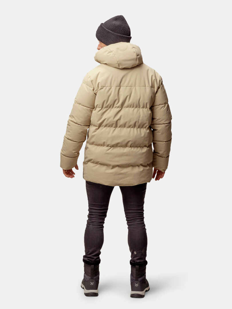 Person i beige Halti Sammal Vadderad Parkajacka Herr, mörka byxor, gråa skor och mössa, sedd bakifrån.