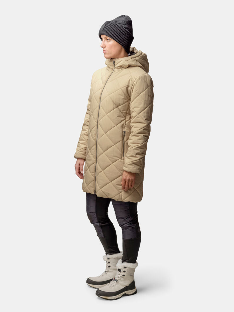 Person med Halti Haapa Vadderad Jacka Dam, svart mössa, svarta leggings och ljusgrå vinterkängor, står i sidled.