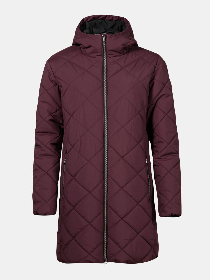 Halti Haapa Vadderad Jacka Dam Plus är en lång rödbrun quiltad parkas med huva och dragkedja fram på vit botten.