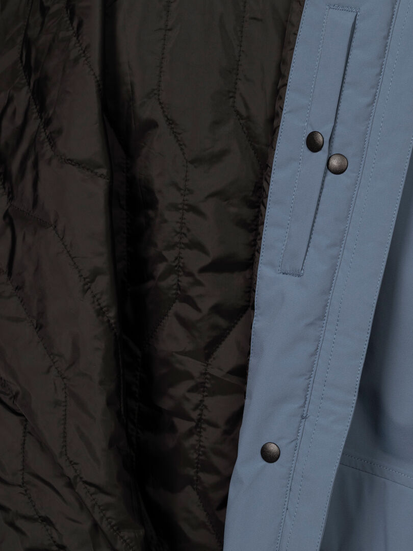 Närbild på Halti Kortteli DX Insulated Parka Dam, med quiltat svart foder, blåt yttertyg och svarta tryckknappar.