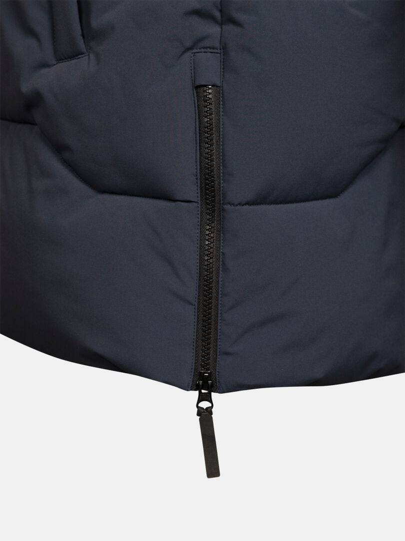 Närbild på den svarta dragkedjan på Halti Brahe Puffer Parka Herr, en mörk vinterjacka, med synlig dragkedjetapp.