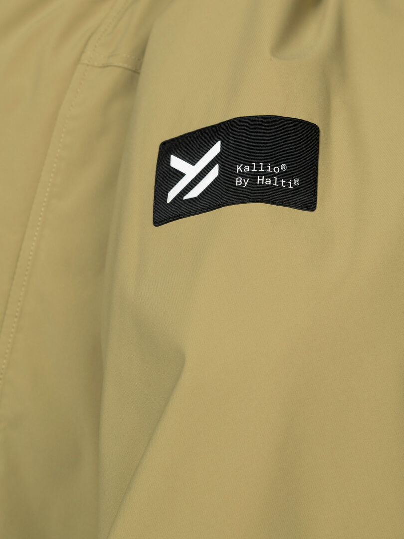 Närbild på den beige, vattenavvisande Kortteli DX Insulated Parka Herr från Halti, där man ser påsydd detalj och logotyp – perfekt för friluftsliv.