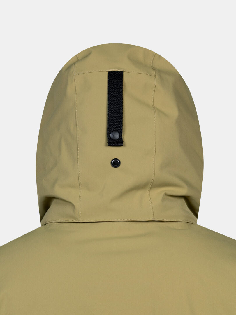 Närbild på baksidan av en beige Halti Kallio DX Parka Herr med ett svart band försett med en knapp och en ögla.