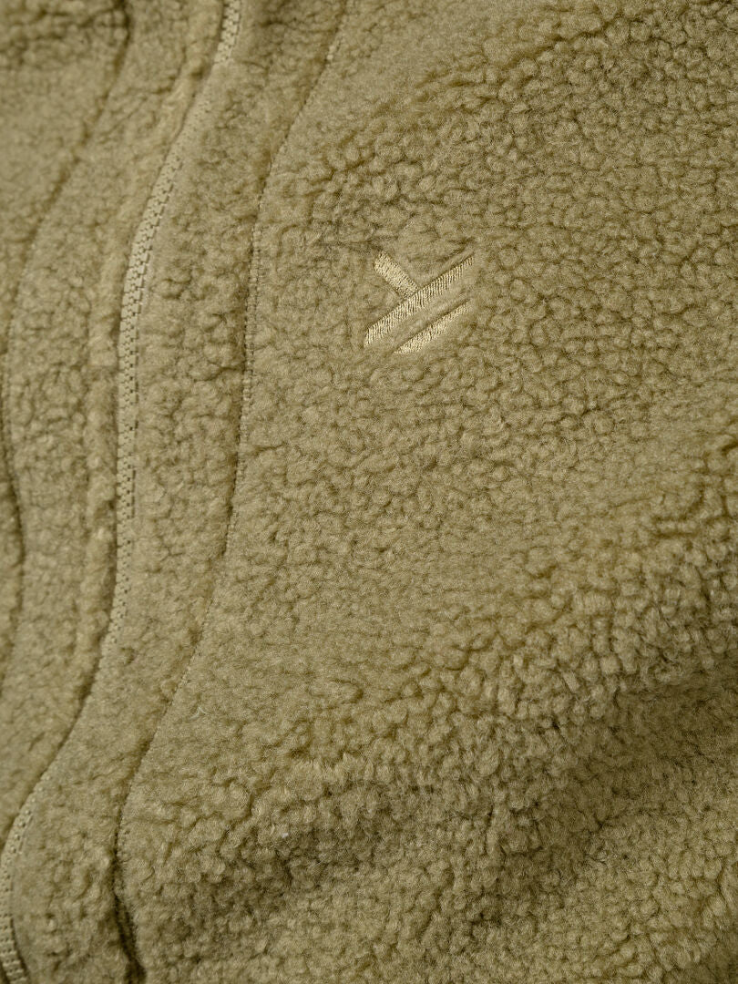 Närbild på Halti Lykky Fleece Väst Unisex i beige, med dragkedja och liten logotyp, tillverkad av återvunnen polyester.