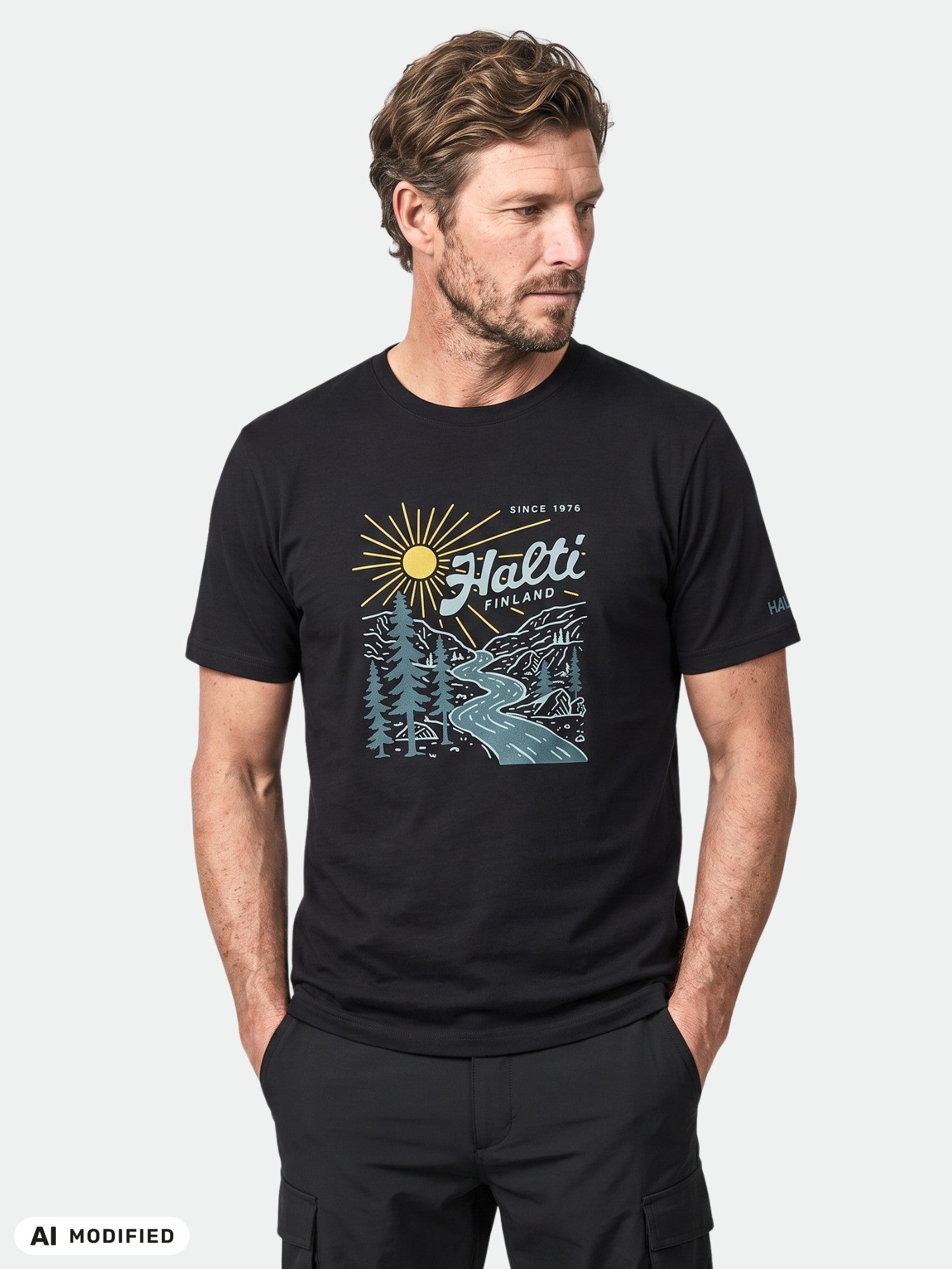 Man i en Halti Vehka Unisex-T-shirt, en mjuk bomullströja med tryck av sol, träd och flod, perfekt för vardagsbruk.