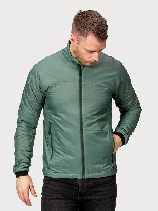 En man bär en grön Halti Neon Jacka Herr med PrimaLoft-fyllning och står med ena handen i fickan.