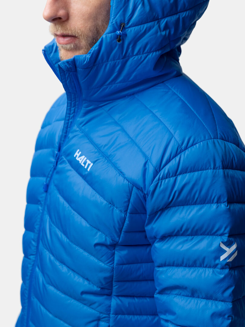 En person bär en ljusblå Halti Huippu Dunjacka Herr med huva, Pertex Quantum och en synlig Halti-logotyp.