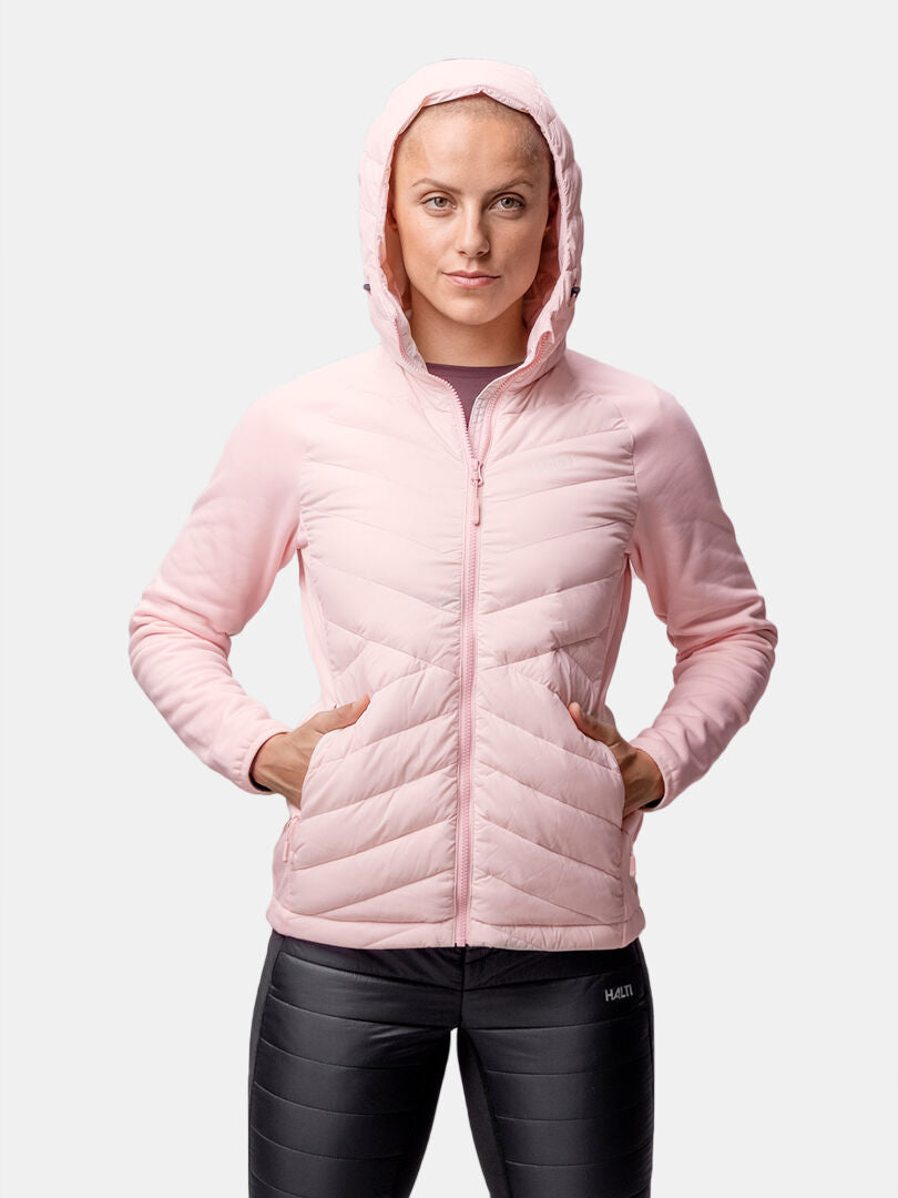 Person som bär Halti Huippu Hybrid Dunjacka Dam i ljusrosa med Pertex Quantum, tillsammans med svarta leggings.