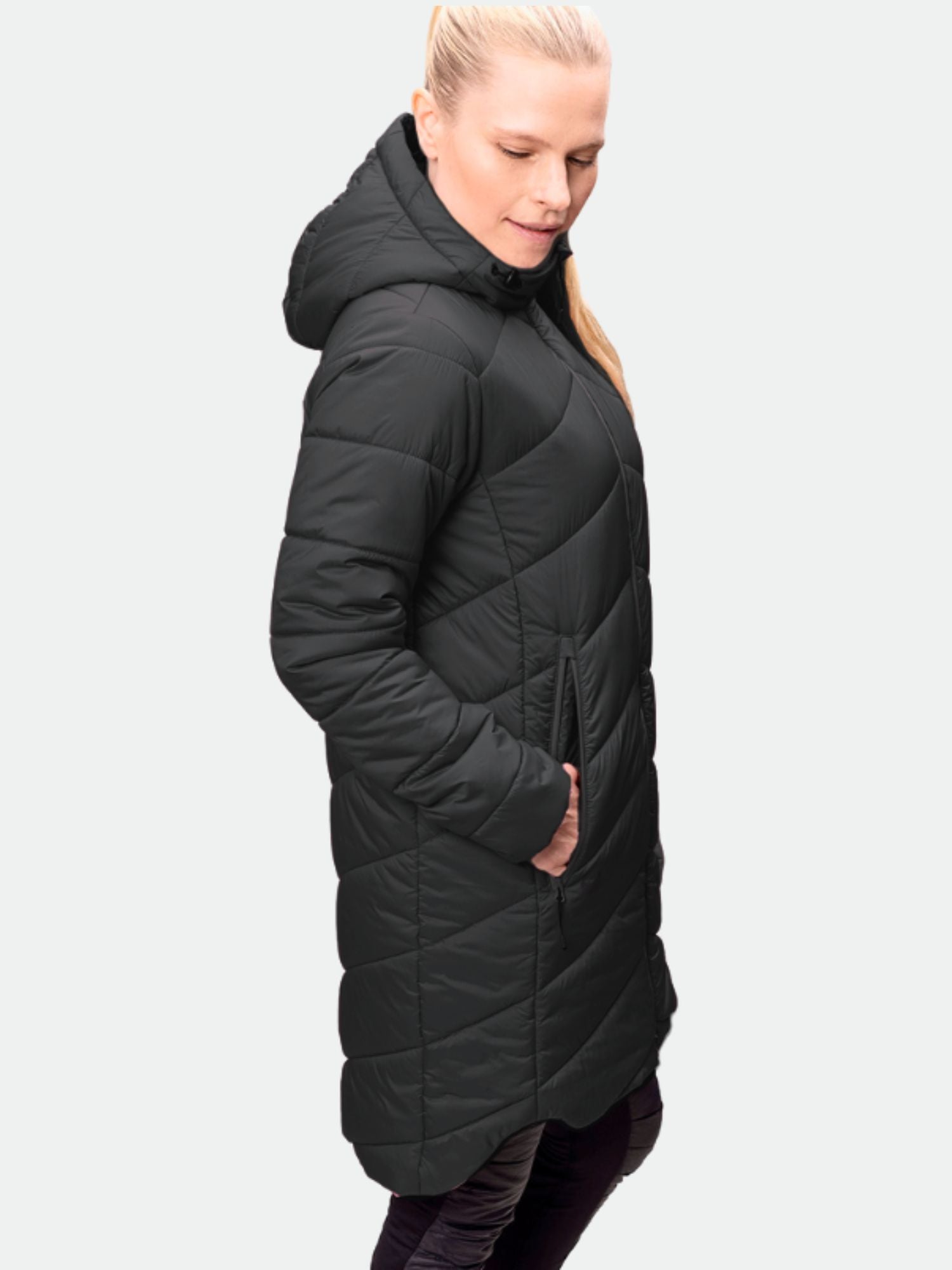 En kvinna bär Halti Komu Lätt Vadderad Parka Dam med händerna i fickorna, stående i sidled.