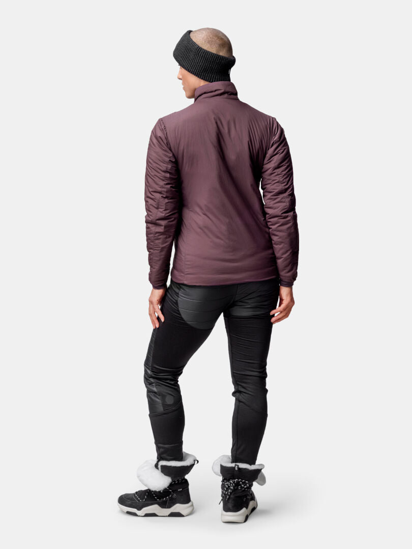 Person vänd bort, klädd i Halti Haave Insulation Primaloft Jacka Dam i lila, svarta byxor, stövlar och ett mörkt pannband.