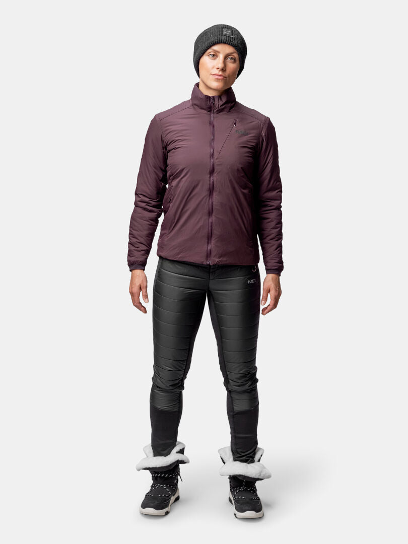 Person i Halti Haave Insulation Primaloft Jacka Dam, mössa, rödbrun jacka, svarta byxor och pälskantade stövlar.