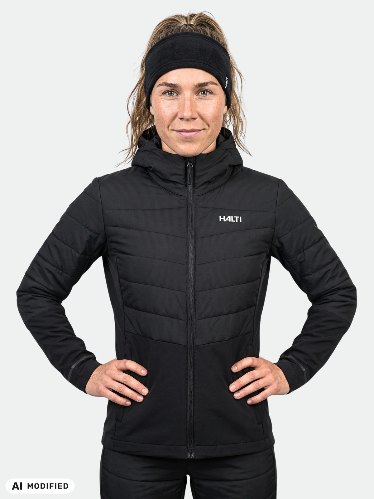 En kvinna klädd i en svart, quiltad Halti Valimo Hybrid Insulation Jacka Dam med huva.