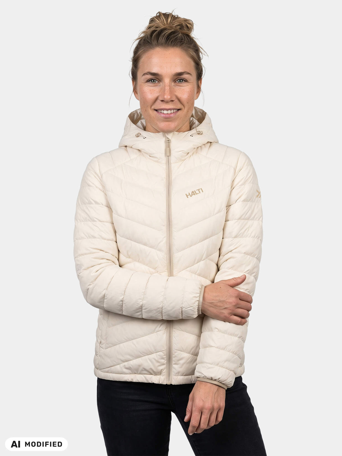 En kvinna klädd i en ljusfärgad Halti Huippu Untuvia Dunjacka Dam med huva och ett quiltat Microtherm Dynamic-mönster.