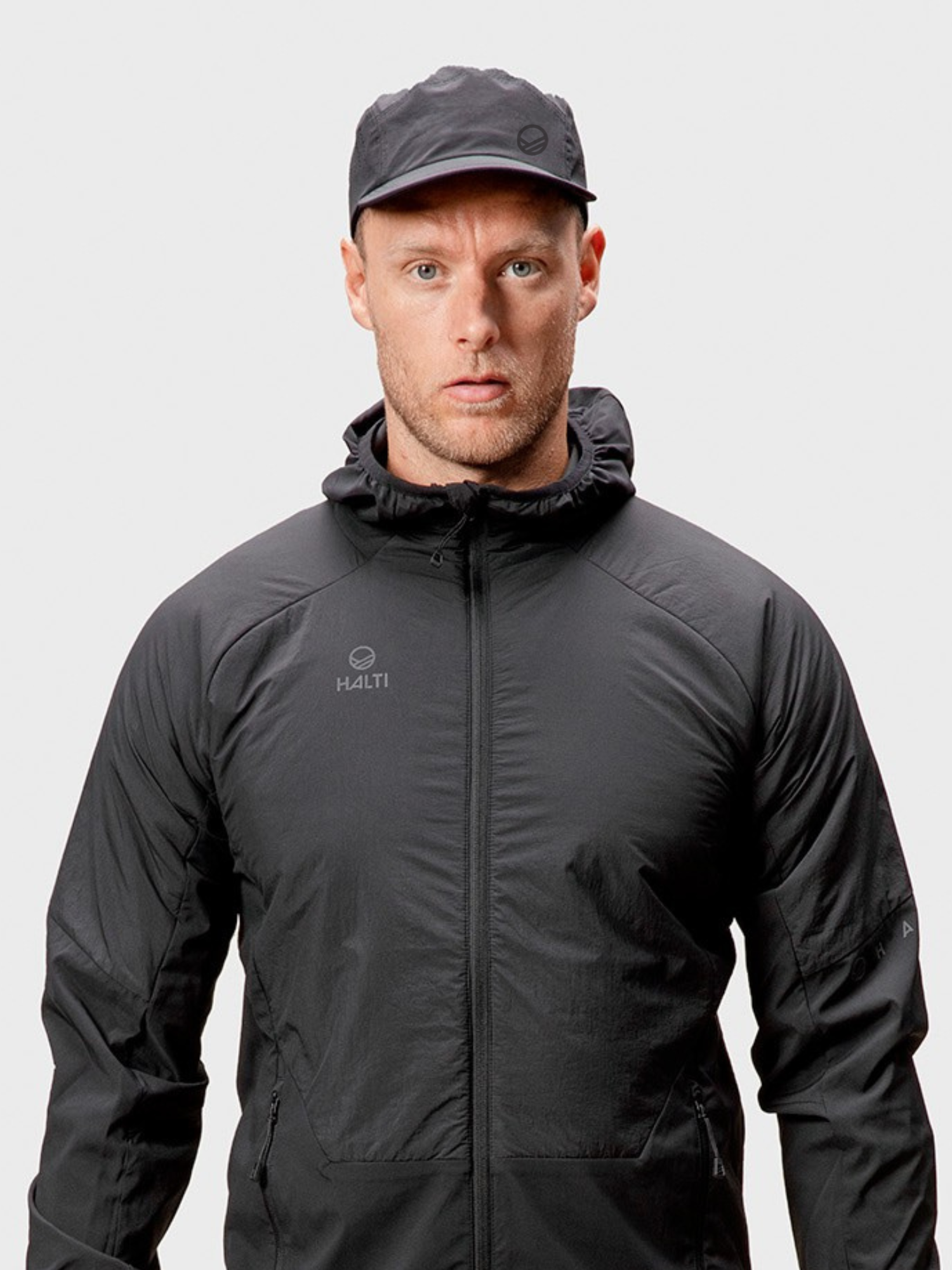 En man i svart jacka och Halti Aero II Keps vetter framåt mot en vit bakgrund.