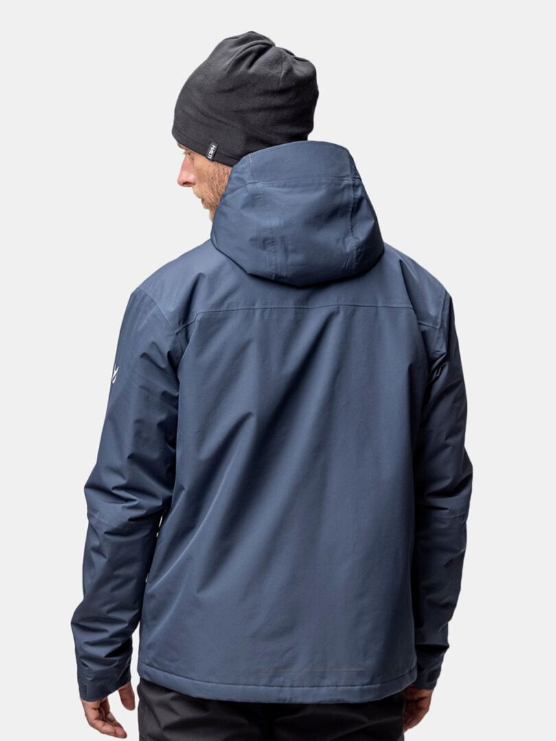 En person i Halti Trone Fleece Mössa och blå jacka med huva, sedd bakifrån, klädd för vinterträning.