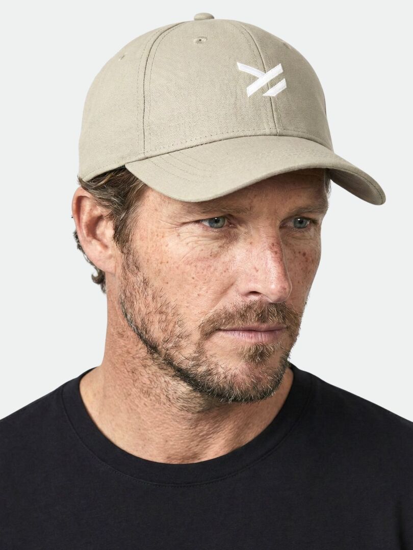 Man i Halti Notsgi Keps av ekologisk bomull och svart crew-neck skjorta ser lätt ut åt sidan.