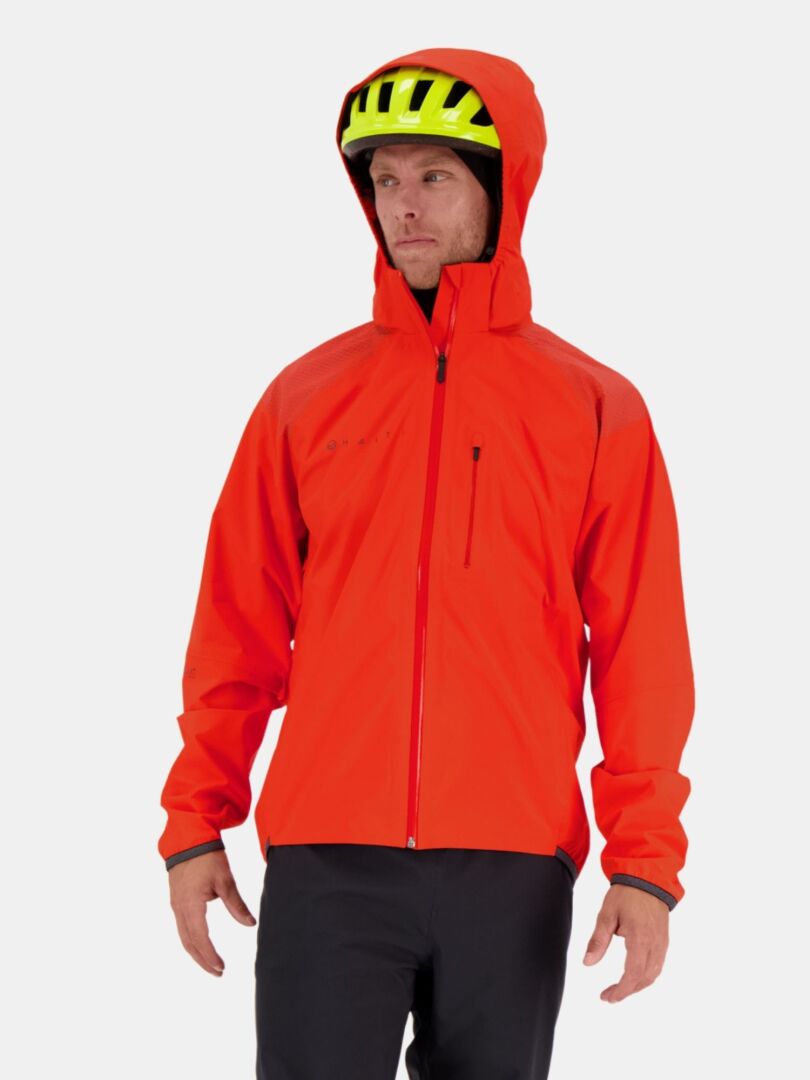 En man bär Halti Liike Herr 3L DrymaxX Sport Jacka i klarorange, tillverkad av återvunnen polyester.