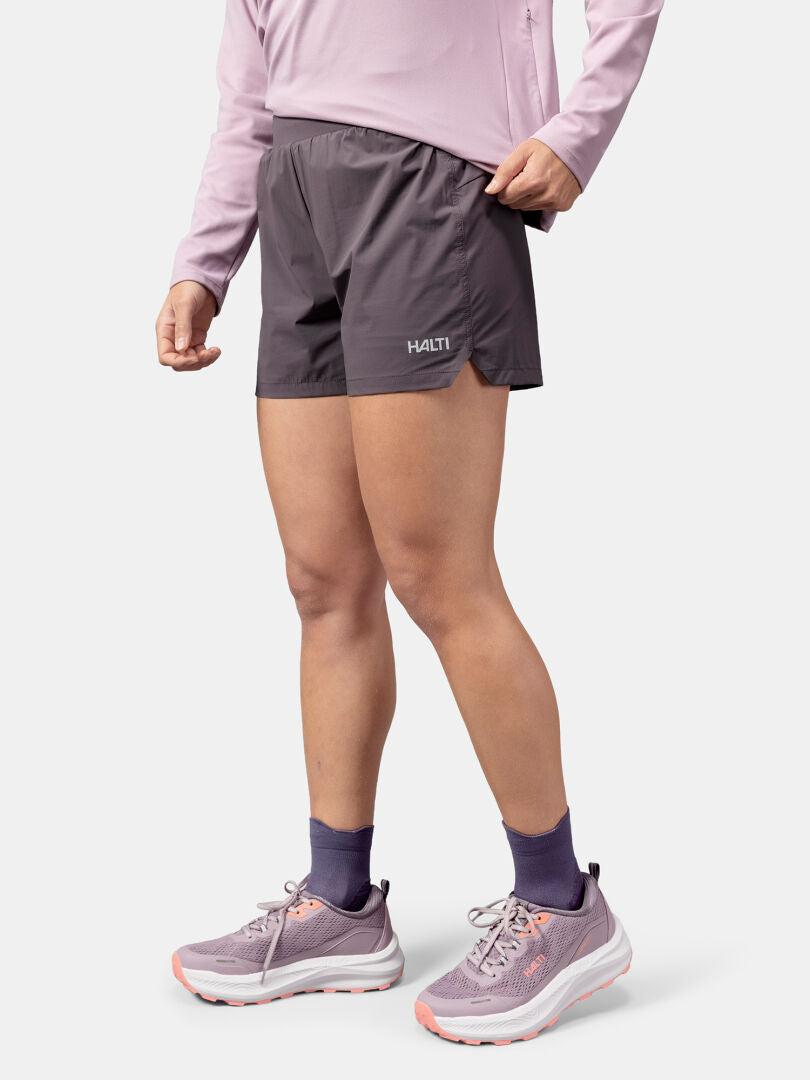 Person i ljuslila långärmad tröja, Halti Uurto Shorts Dam, lila strumpor och löparskor.