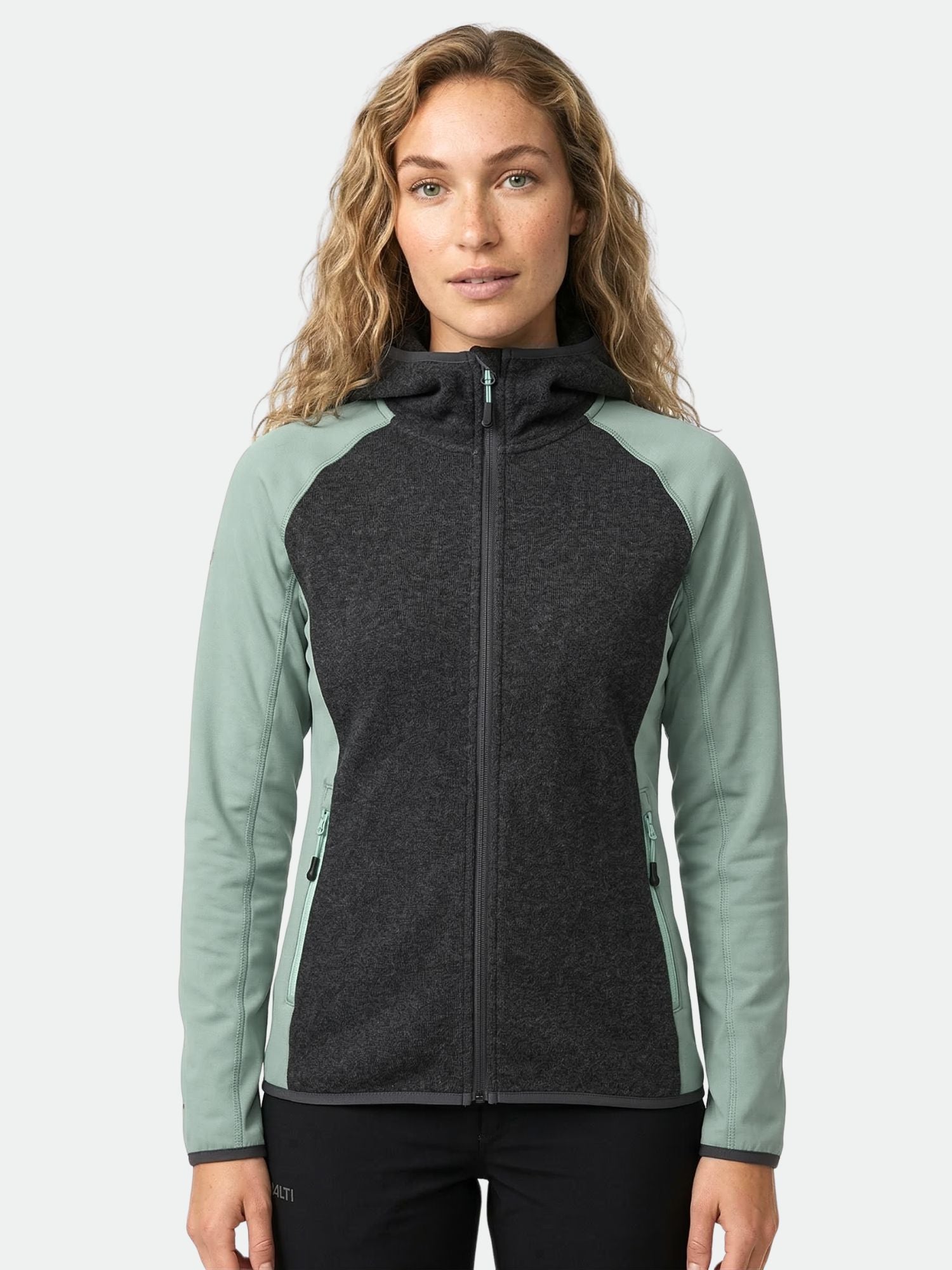 Kvinna i Halti Circuit II Huvtröja Dam, en Active Dry hoodie i två färger, mot en enfärgad bakgrund.