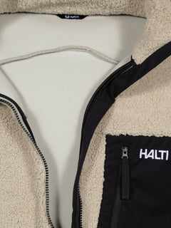 Närbild på Lumista Polar Fleecejacka Herr i beige med svart ficka och Halti-logotyp, perfekt för vandring.