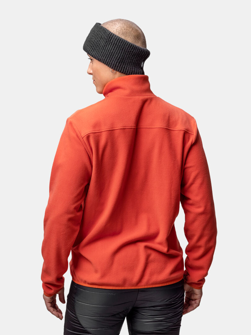 En person i Halti Rockmoon Fleecejacka Dam, svart pannband och svarta byxor, sedd bakifrån mot en enfärgad bakgrund.