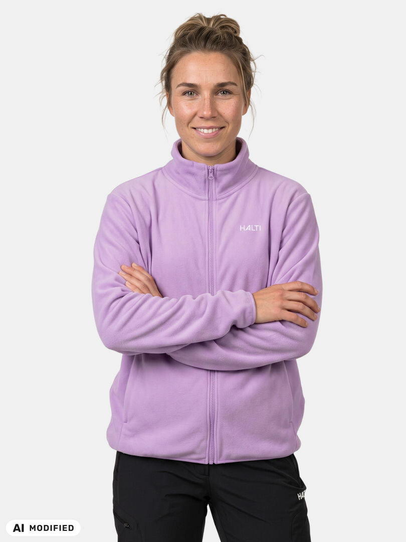En person i en Halti Rockmoon Fleecejacka för dam, med armarna i kors, står framför en enfärgad vit bakgrund.