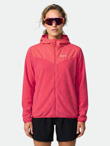 En person bär Halti Rockmoon Fleecehoodie Dam i rosa, svarta shorts och stora tonade solglasögon, vänd framåt.