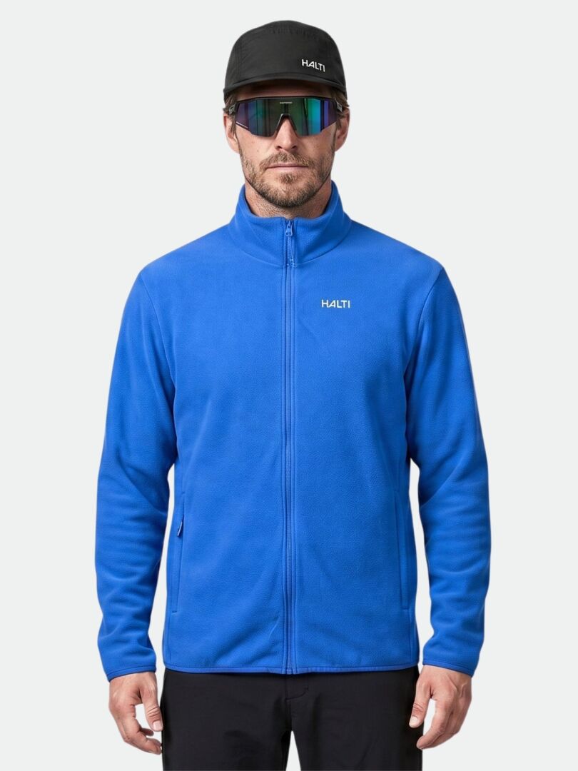 En man bär en Halti Rockmoon-fleecejacka, en svart keps och reflekterande solglasögon framför en enkel bakgrund.