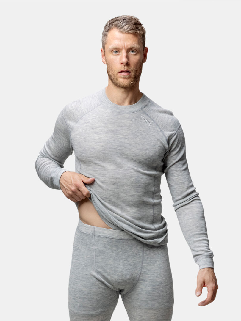 Man i Halti Hossa II Merino Underställ Set Herr lyfter på sin skjorta och visar en del av sin mage.