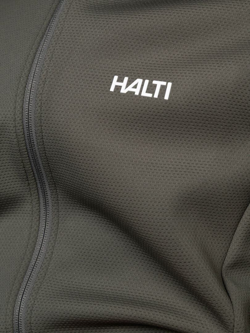 Närbild på en grå Halti Kivikko Mellanlager Herr-jacka med dragkedja och vit HALTI-logotyp på bröstet.