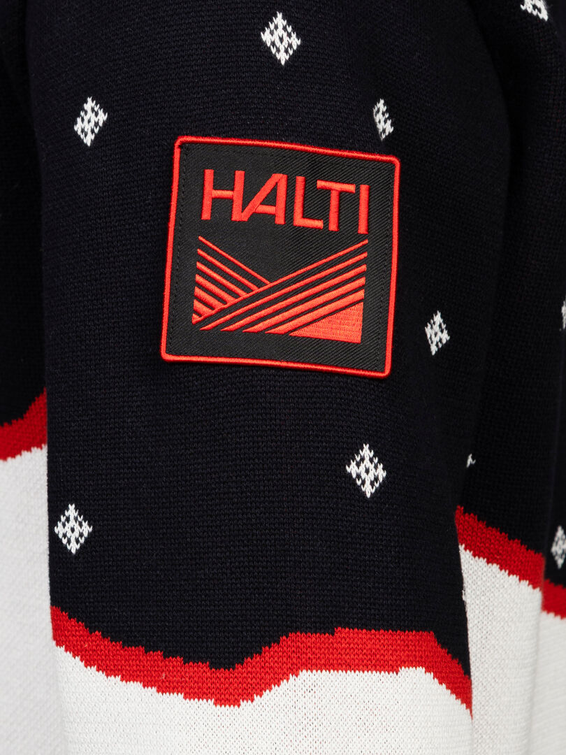 Närbild på en svart Halti Tauko Unisex-tröja med vita rombmönster och en röd-svart logotyp-patch på ärmen.