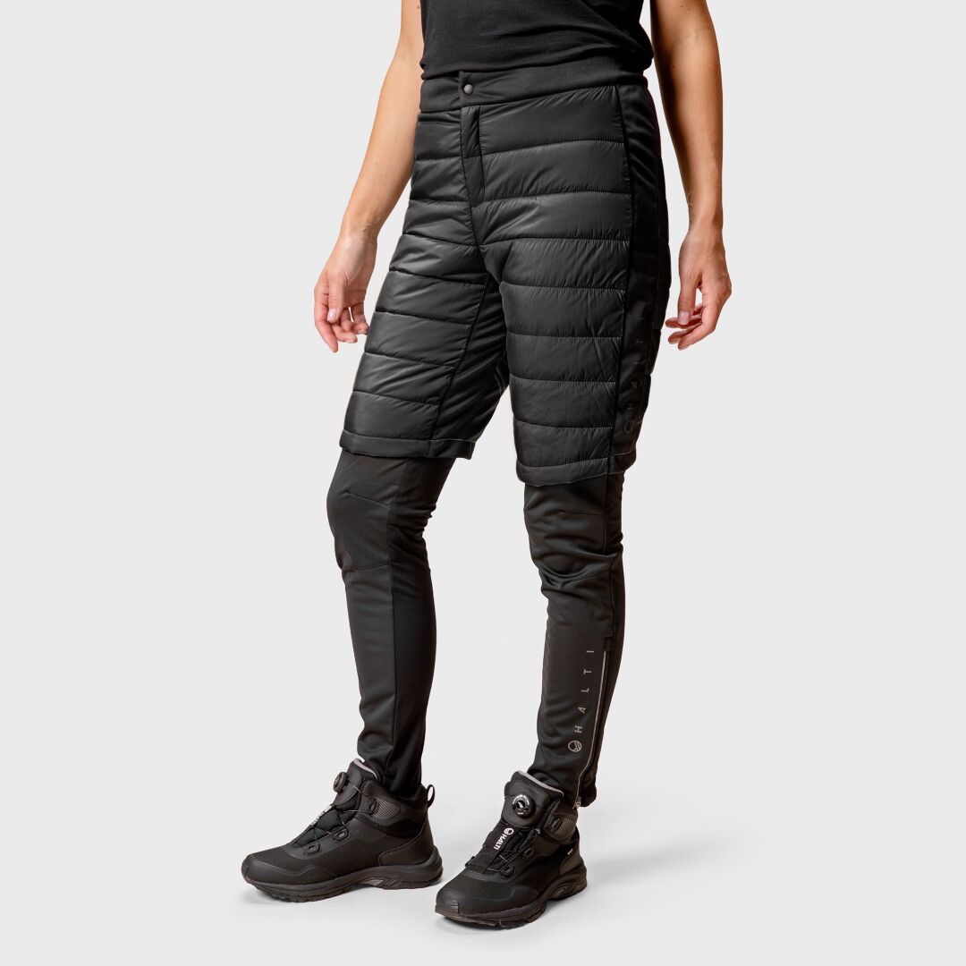 En person i Halti Hanki Warm Hybrid Shorts Dam över svarta leggings och vandringskängor, redo för vinterlek.